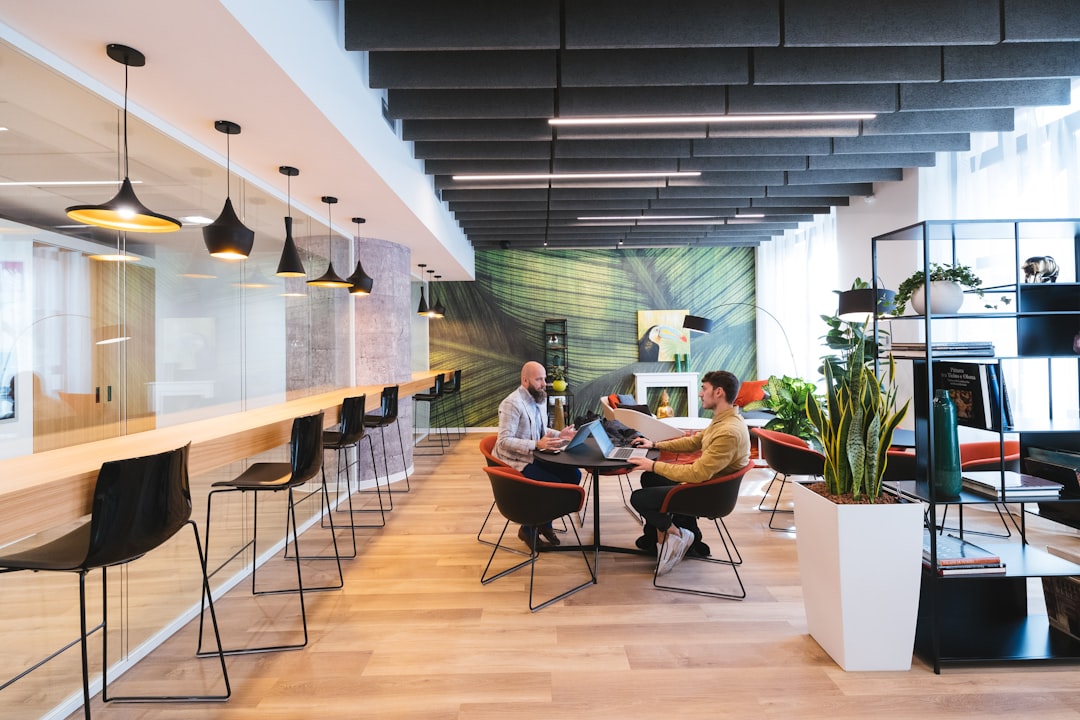 A professional real estate agent and a client having a meeting in a bright, modern office to discuss property details and review documents.
