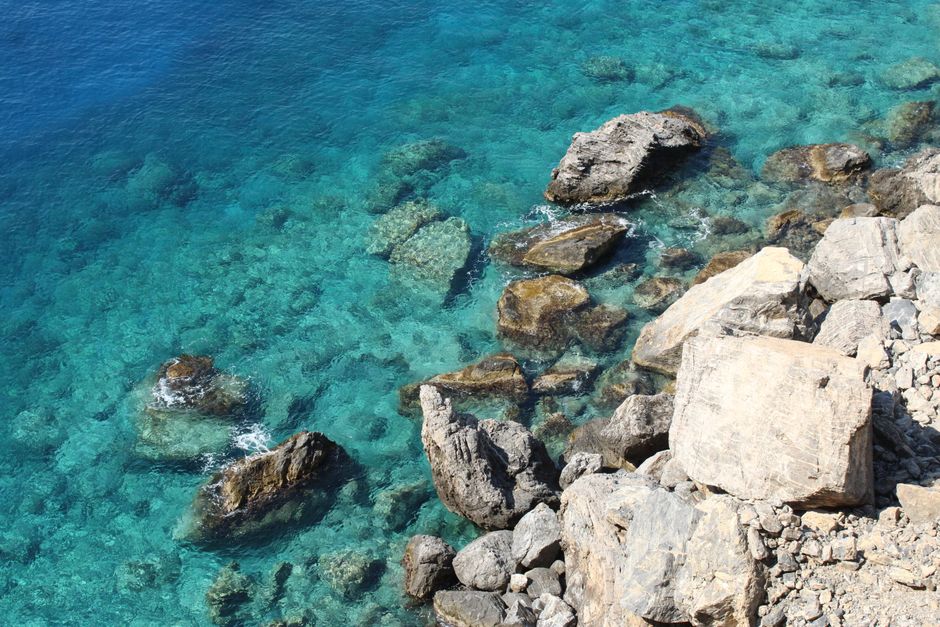 Sunlight penetrates crystal clear water to reveal the smooth rocks below, a metaphor for financial transparency and seeing through the murky details of a large transaction.